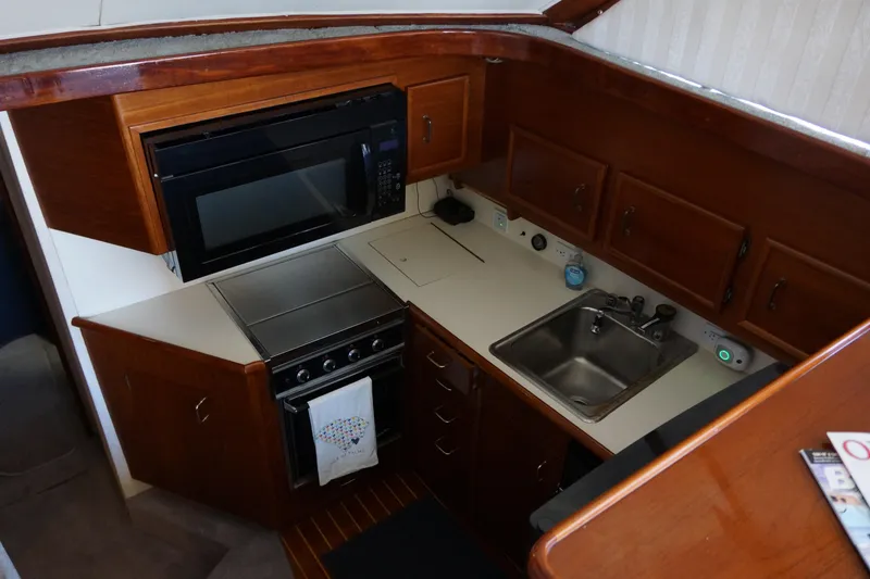 Slide: The Image of 1988 Ocean Yachts Super Sport kitchen with wood cabinetry, microwave, stove, and sink. - 8