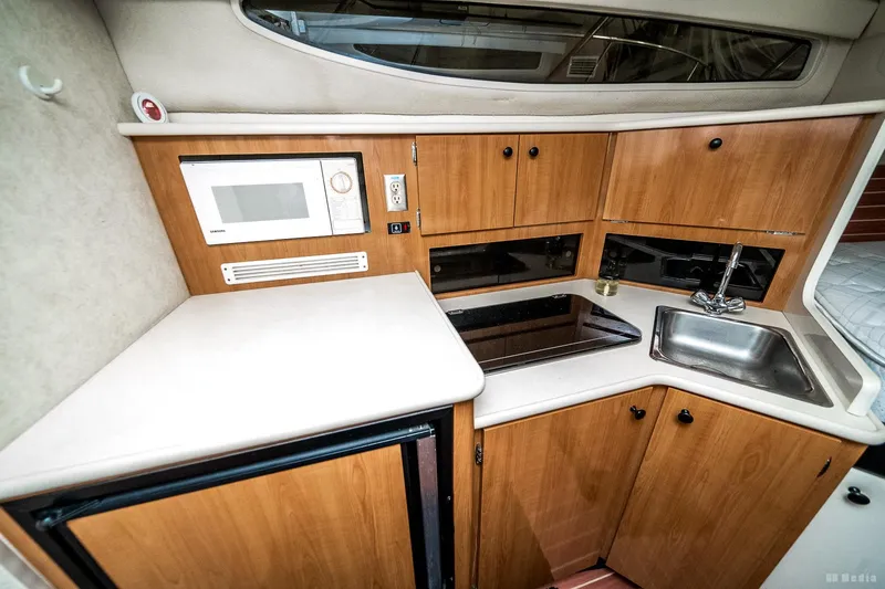 Slide: The Image of 2001 Bayliner 3055 Ciera boat kitchen with microwave, sink, and wooden cabinets. - 6