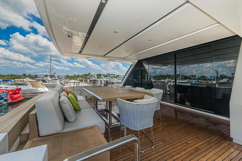 Slide: The Image of Luxury Sanlorenzo SL104 yacht deck with seating, dining table, and marina view. - 16