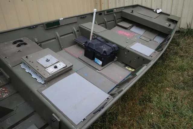 Slide: The Image of 2020 Lowe 1448T boat interior with storage compartments and battery box, parked on grass. - 3
