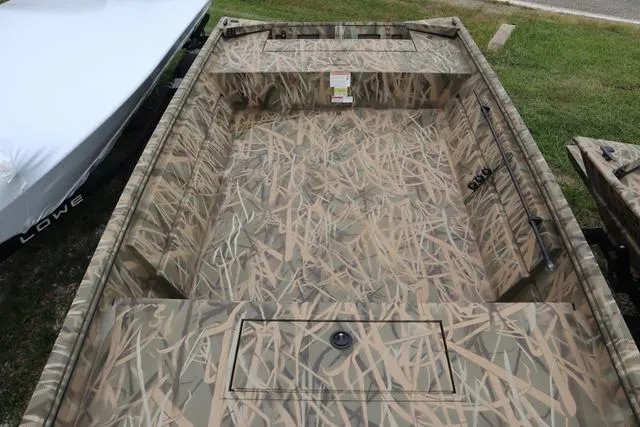 Slide: The Image of 2025 Lowe Roughneck 1760 Tiller boat with camouflage interior design on grass. - 5