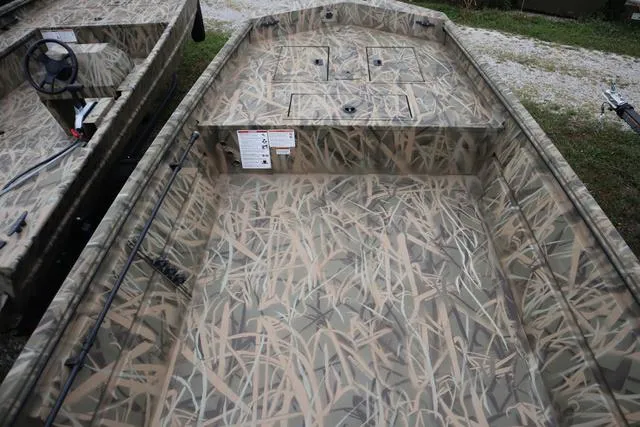 Slide: The Image of 2025 Lowe Roughneck 1760 Tiller boat with camouflage interior design, parked outdoors. - 6