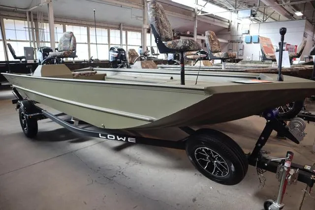 Slide: The Image of 2025 Lowe Roughneck 1860 Rambler boat in showroom, featuring camouflage seats and trailer. - 10