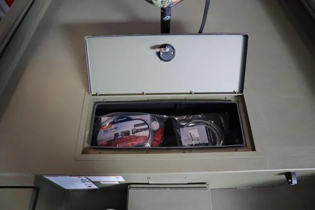 Slide: The Image of Storage compartment in 2025 Lowe Roughneck 1860 Rambler boat, containing cables and accessories. - 19