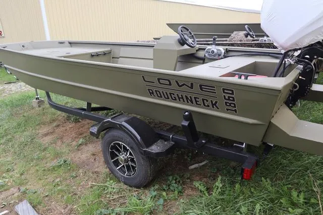 Slide: The Image of 2025 Lowe Roughneck 1860 Rambler boat on trailer, parked on grass. - 2