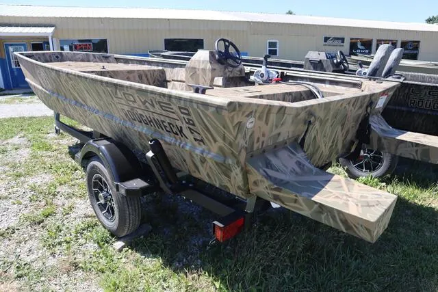 Slide: The Image of 2025 Lowe Roughneck 1760 boat with add-on console, camo design, on trailer outdoors. - 3