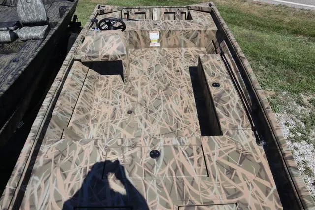 Slide: The Image of 2025 Lowe Roughneck 1760 boat with camo design and add-on console, parked on grass. - 6