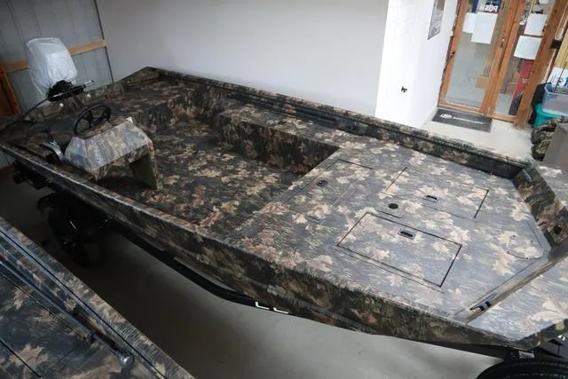 Slide: The Image of 2024 Lowe Roughneck 1760 boat with camo design and add-on console in showroom. - 3