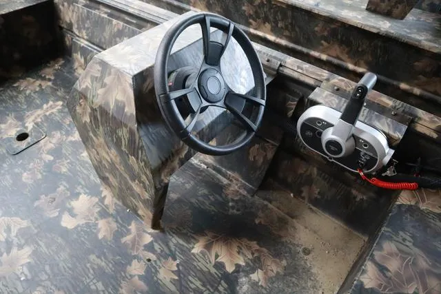 Slide: The Image of 2024 Lowe Roughneck 1760 boat console with camouflage design and steering wheel. - 4