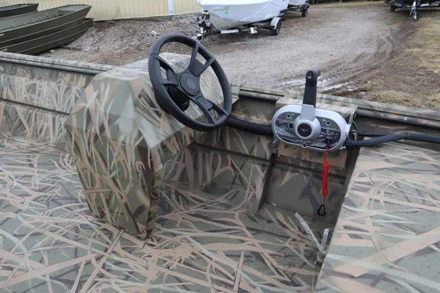 Slide: The Image of 2025 Lowe 2070 boat with camo console and steering wheel, parked on gravel. - 14