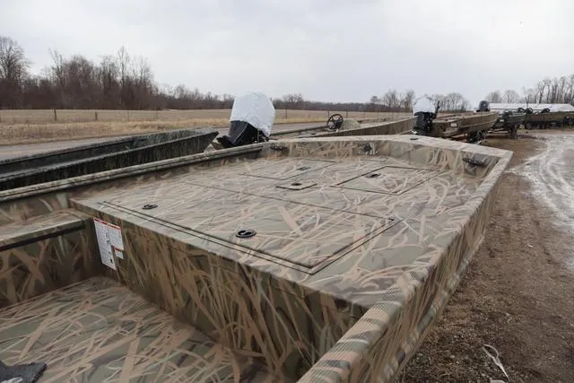 Slide: The Image of 2025 Lowe 2070 boat with add-on console, camo design, parked outdoors on a cloudy day. - 5