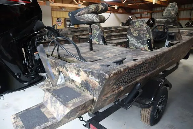 Slide: The Image of 2024 Lowe Roughneck 1760 SC Jet boat with camouflage design in a storage facility. - 3