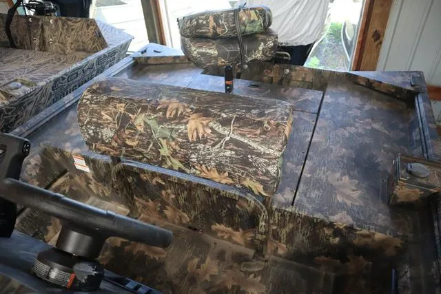 Slide: The Image of 2024 Lowe Roughneck 1860 CC boat interior with camouflage seating and steering wheel. - 4