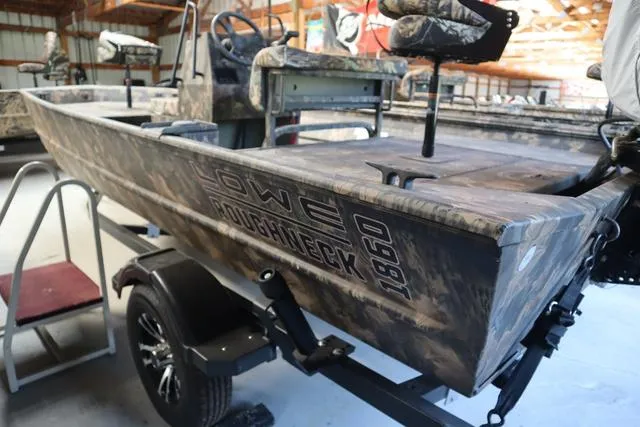 Slide: The Image of 2024 Lowe Roughneck 1860 CC boat in camouflage, displayed on a trailer in a showroom. - 7