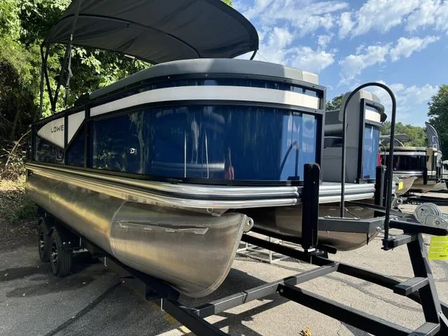 Slide: The Image of 2025 Lowe LS 190 pontoon boat on trailer, under a clear blue sky. - 1