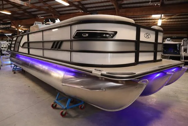 Slide: The Image of 2025 Bentley Pontoons Elite 253 Swingback Triple Tube with blue underglow in a showroom. - 46