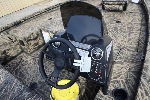 Slide: The Image of 2024 Lowe Stinger 175 Poly Camo boat interior with steering console and camouflage design. - 8