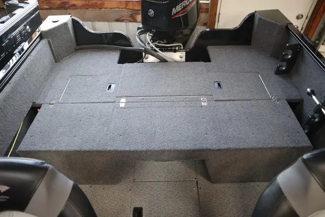 Slide: The Image of 2025 Crestliner 1650 Kodiak SC boat interior with carpeted deck and Mercury engine. - 6