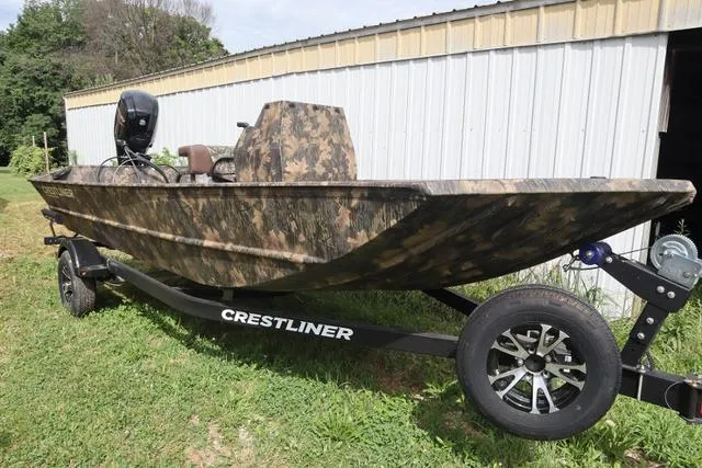 Slide: The Image of 2024 Crestliner 1870 Retriever FCC Tunnel boat on trailer, camo design, parked outdoors. - 1