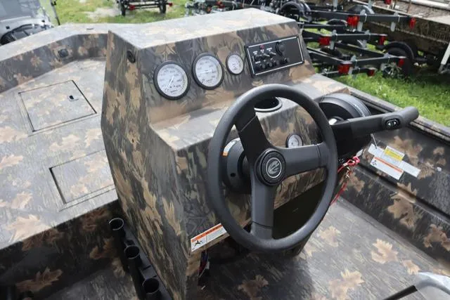 Slide: The Image of 2024 Crestliner 1870 Retriever FCC Tunnel boat dashboard with camo design and steering wheel. - 6