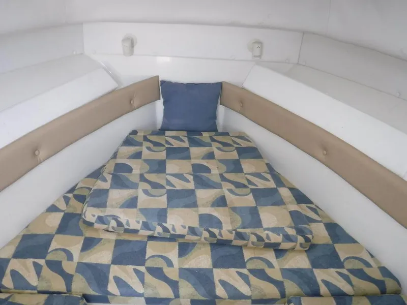 Slide: The Image of 2008 Pro-Line 26 XP boat cabin with patterned bedding and blue pillow. - 8