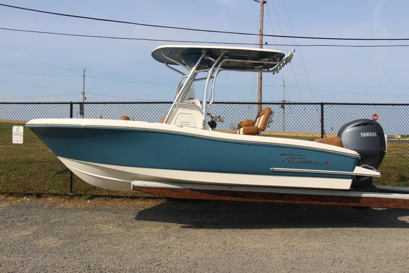 Slide: The Image of 2025 Pioneer 202 Islander boat with Yamaha engine, parked on gravel near a fence. - 5