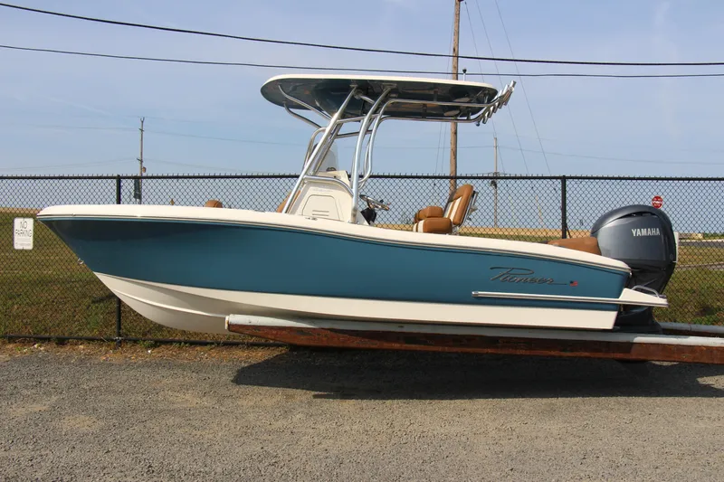Slide: The Image of 2025 Pioneer 202 Islander boat with Yamaha engine, parked on gravel near a fence. - 7