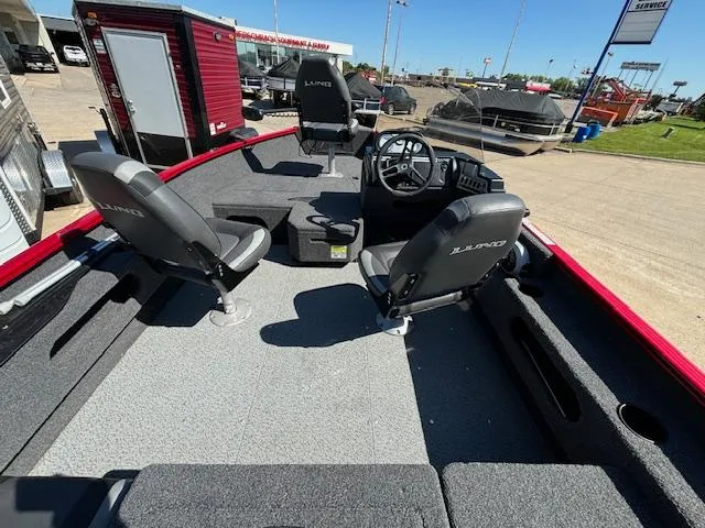 Slide: The Image of 2022 Lund 1675 Adventure SS boat interior with seating and steering wheel, parked outdoors. - 10