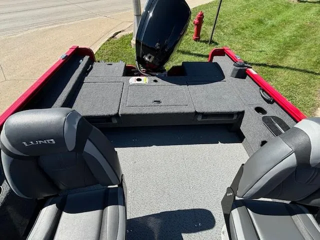 Slide: The Image of 2022 Lund 1675 Adventure SS boat interior with seating and motor, parked on grass. - 26