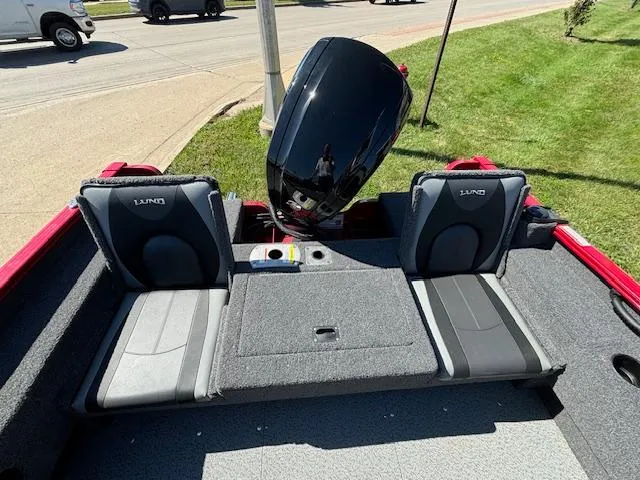 Slide: The Image of 2022 Lund 1675 Adventure SS boat interior with seating and motor, parked on grass. - 27