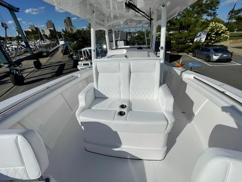 Slide: The Image of 2023 Southport 33 FE boat with white seating and cup holders, docked at a marina. - 10