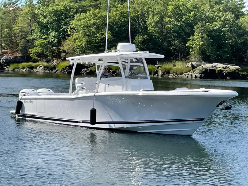 Slide: The Image of 2023 Southport 33 FE boat cruising on a calm lake with lush greenery. - 14
