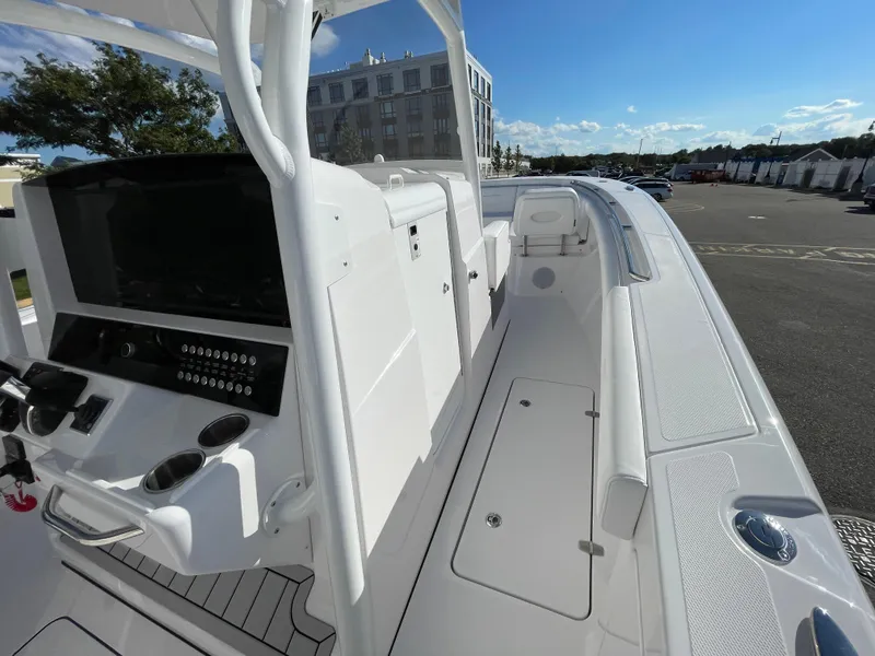Slide: The Image of 2023 Southport 33 FE boat interior with modern console and seating, docked under clear skies. - 8