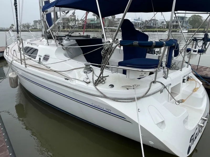 Slide: The Image of 2008 Catalina 309 sailboat docked, featuring sleek design and blue canopy. - 8