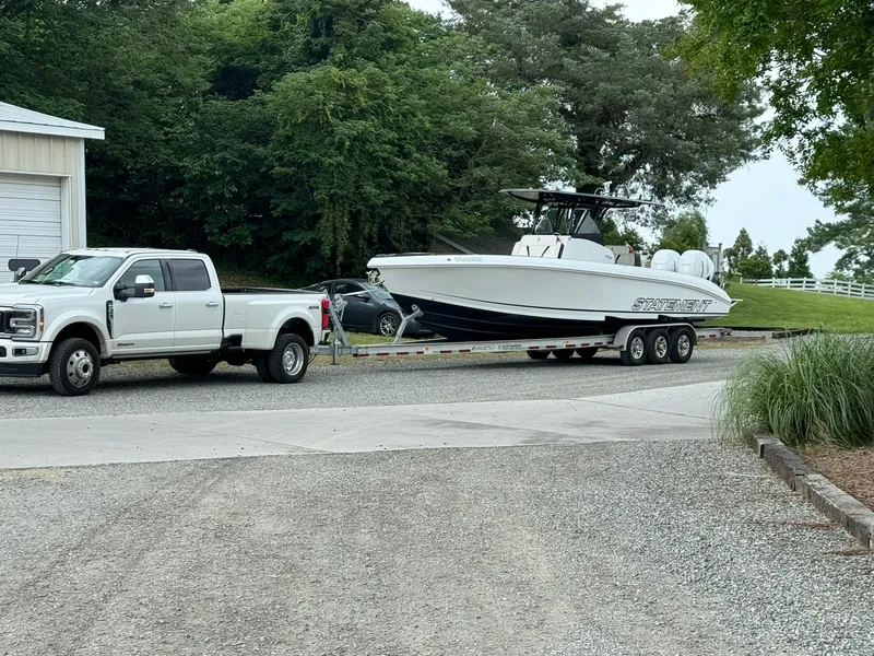 Slide: The Image of White truck towing 2018 Statement 35 CC boat on a trailer, parked on gravel driveway. - 14