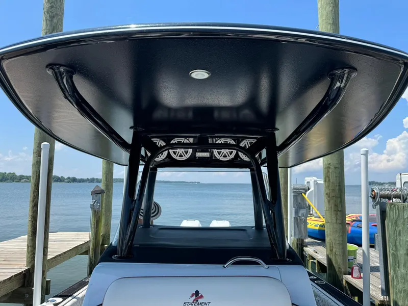 Slide: The Image of 2018 Statement 35 CC boat docked, featuring a sleek T-top and scenic waterfront view. - 8