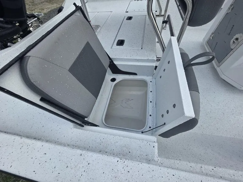 Slide: The Image of 2025 Xpress H22B boat seat with storage compartment, open on a speckled deck. - 10