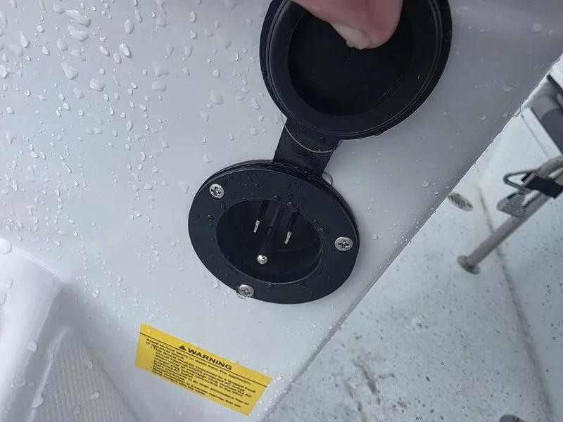 Slide: The Image of Water-resistant power outlet on Xpress H22B boat, 2025 model, with safety warning label. - 20