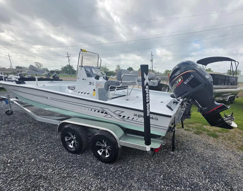 Slide: The Image of 2025 Xpress H22B boat on trailer with outboard motor, parked on gravel. - 7