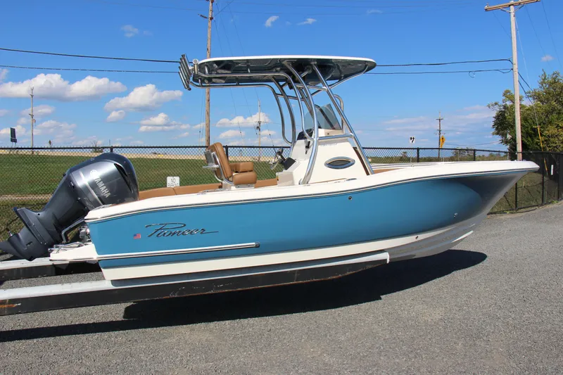 The Image of 2025 Pioneer 222 Sportfish boat with blue hull and outboard motor on a trailer. - 0