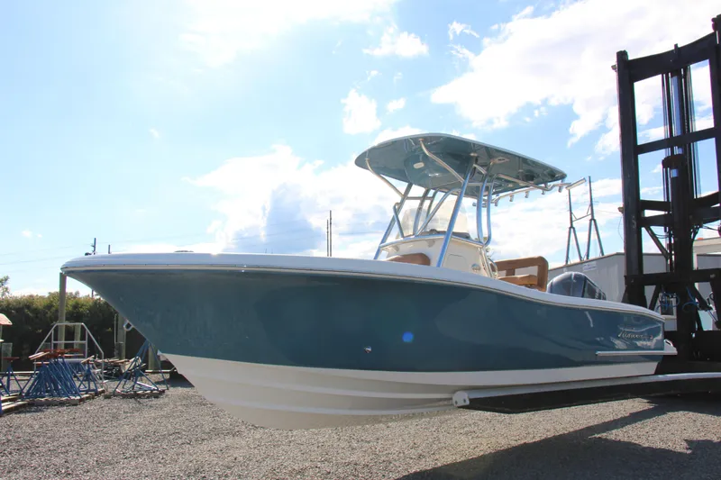 Slide: The Image of 2025 Pioneer 222 Sportfish boat with blue hull, parked outdoors under a clear sky. - 1