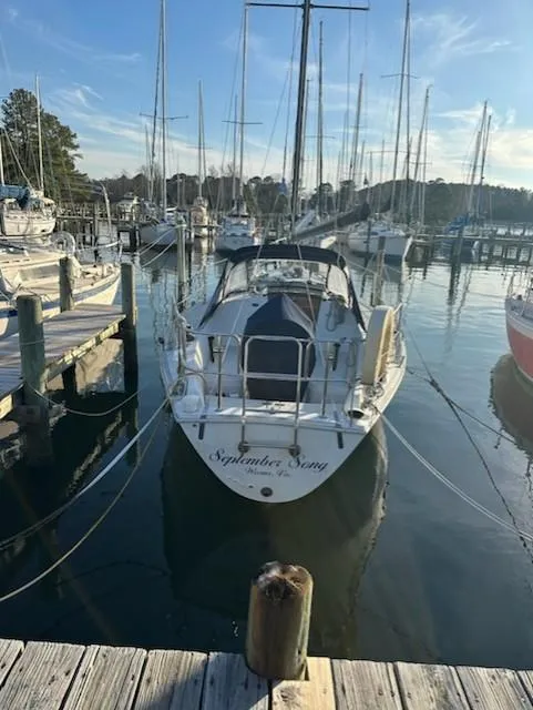 The Image of 1985 Ericson 30 Plus sailboat docked in a marina, surrounded by other boats. - 0