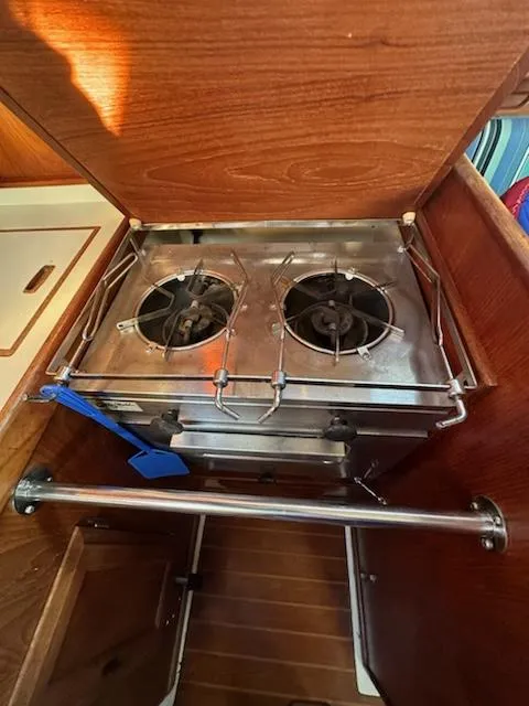 Slide: The Image of 1985 Ericson 30 Plus yacht kitchen with a two-burner stove and wooden cabinetry. - 14