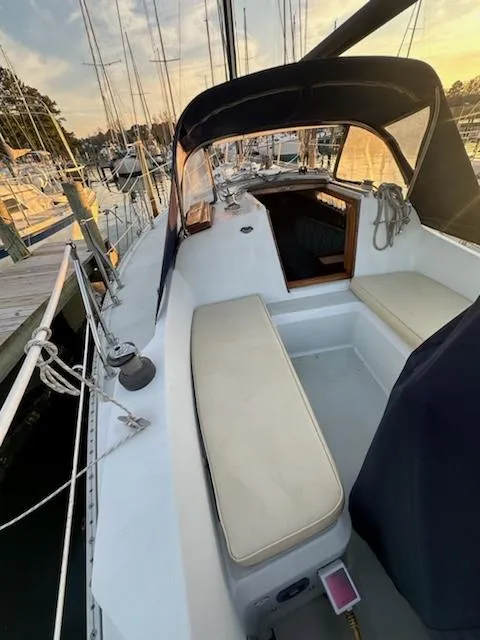 Slide: The Image of 1985 Ericson 30 Plus sailboat with cushioned cockpit, docked at marina during sunset. - 33