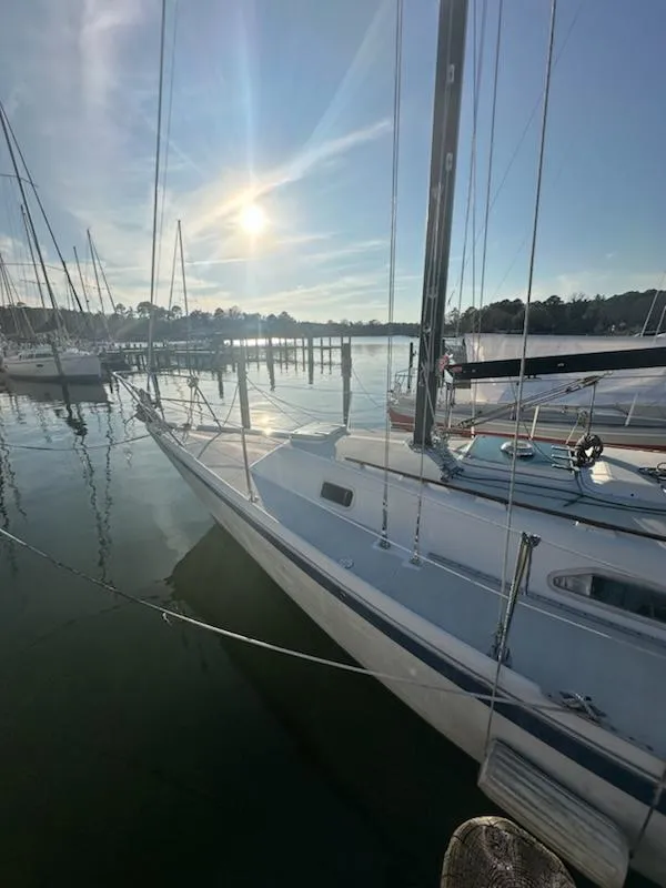 Slide: The Image of 1985 Ericson 30 Plus sailboat docked in a serene marina at sunset. - 44