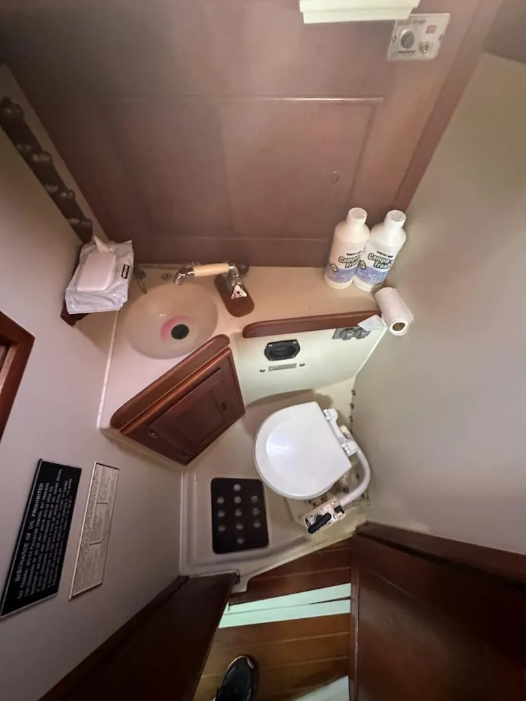 Slide: The Image of Compact bathroom in a 1985 Ericson 30 Plus sailboat with sink, toilet, and storage. - 9
