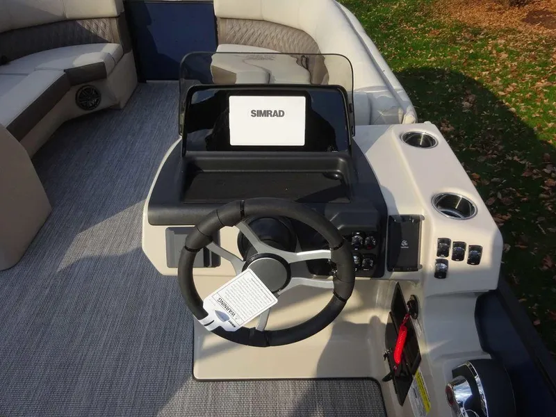 Slide: The Image of 2024 Harris Sunliner 230 boat dashboard with steering wheel and Simrad display. - 13