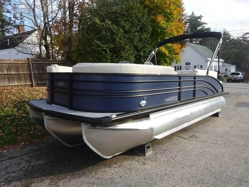 Slide: The Image of 2024 Harris Sunliner 230 pontoon boat parked on a residential street. - 2