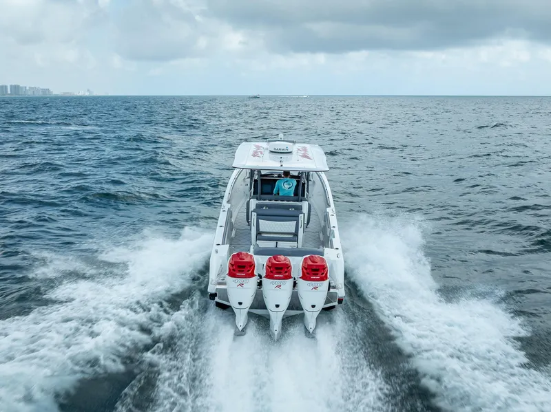 Slide: The Image of 2018 Nor-Tech 390 boat cruising on open water with triple outboard engines. - 14