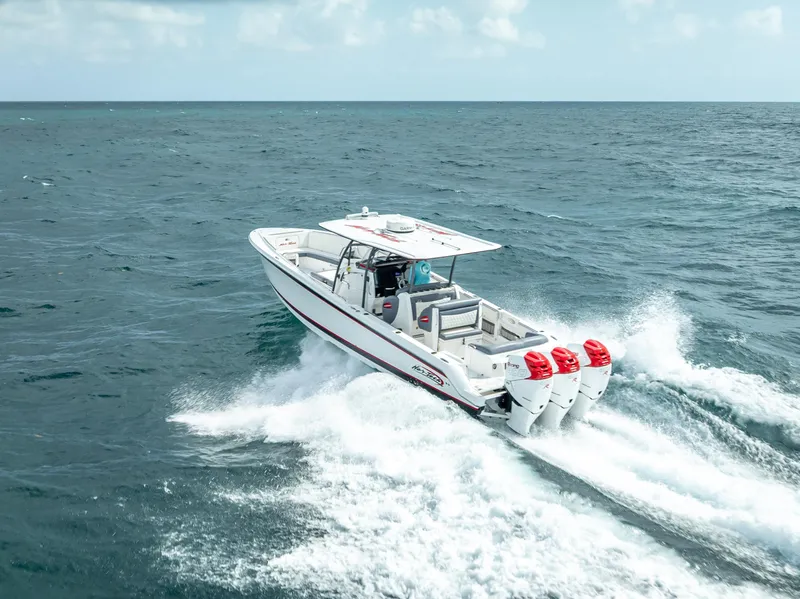 Slide: The Image of 2018 Nor-Tech 390 boat cruising on open water with triple outboard engines. - 20